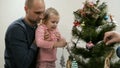 Happy family decorating a Christmas tree with boubles in the living-room