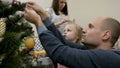 Happy family decorating a Christmas tree with boubles in the living-room