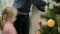 Happy family decorating a Christmas tree with boubles in the living-room