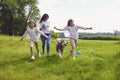 Happy family with a dog in the park. A mother and two daughters run playing with a husky dog on the grass in nature. Royalty Free Stock Photo