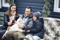 Happy young family with dog sitting on bench in house yard during winter holidays Royalty Free Stock Photo