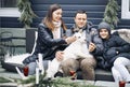 Happy family with dog sitting on bench in house yard during winter holidays Royalty Free Stock Photo