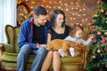 Happy family with a dog sitting in a room on the sofa near the festive Christmas tree Royalty Free Stock Photo