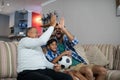 Happy family doing high five while watching soccer match