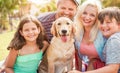 Happy family doing picnic in nature outdoor - Young parents having fun with children and their pet in summer time laughing,