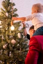 Young Happy Family Dressing Up The Christmas Tree. Back view