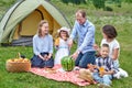Happy family eating watermelon at picnic in meadow near the tent. Family Enjoying Camping Holiday In Countryside Royalty Free Stock Photo