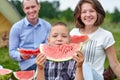 Happy family eating watermelon at picnic in meadow near the tent. Mother, father and child Enjoying Camping Holiday In Countryside Royalty Free Stock Photo