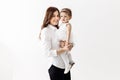 Happy family. Emotional young stylish mother staying and holding in arms laughing adorable toddler baby daughter, having