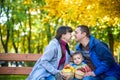 Happy family enjoying autumn picnic. Father mother and son sit on bench with apples basket. Happy family leisure together concept Royalty Free Stock Photo