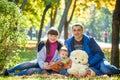 Happy family enjoying autumn picnic. Father mother and son sit on field with apples basket teddy bear and reading book. Happy Royalty Free Stock Photo