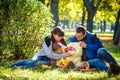 Happy family enjoying autumn picnic. Father mother and son sit on field with apples basket teddy bear and reading book. Happy Royalty Free Stock Photo