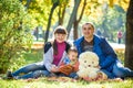 Happy family enjoying autumn picnic. Father mother and son sit on field with apples basket teddy bear and reading book. Happy Royalty Free Stock Photo