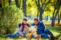 Happy family enjoying autumn picnic. Father mother and son sit on field with apples basket teddy bear and reading book. Happy Royalty Free Stock Photo