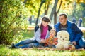 Happy family enjoying autumn picnic. Father mother and son sit on field with apples basket teddy bear and reading book. Happy Royalty Free Stock Photo