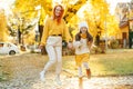 Happy family enjoying autumn weather in the park. Lovely girl with her mom having fun on the walk Royalty Free Stock Photo