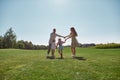 Happy family enjoying leisure activity, spending time together with two little kids, boy and girl in green park on a Royalty Free Stock Photo