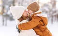 Happy family enjoying snowy weather outdoor, mom with little son hugging during walk in winter park Royalty Free Stock Photo