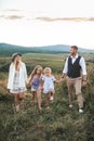 Happy family enjoying time together at summer sunset field outdoor. Young happy family with two daughters having fun at Royalty Free Stock Photo