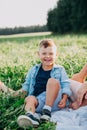 Happy family enjoying together in summer day. Little boy sitting on grass Royalty Free Stock Photo