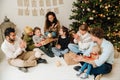 Happy family exchanging and opening gifts while sitting near Christmas tree Royalty Free Stock Photo