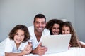 Happy family of family using laptop together on bed Royalty Free Stock Photo