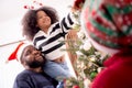 Happy family with father carry daughter decorating ornament on Christmas tree together at home, thanksgiving eve. Royalty Free Stock Photo