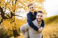 Happy family father and child boy in the autumn leaf fall in park holding his child on his back Royalty Free Stock Photo