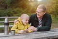 Happy Family: Father And Child Boy Son Playing And Laughing In Autumn Park, Sitting On Wooden Bench And Table. Father Royalty Free Stock Photo