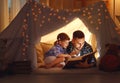 Happy family father and child daughter reading a book in tent Royalty Free Stock Photo