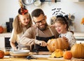 Happy family father and children prepare for Halloween by carving pumpkins at home in kitchen