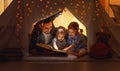 Happy family father and children reading a book in tent at hom Royalty Free Stock Photo