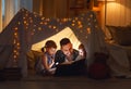 Happy family father and children reading a book in tent at hom Royalty Free Stock Photo