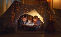 Happy family father and children reading a book in tent at hom Royalty Free Stock Photo