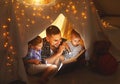 Happy family father and children reading a book in tent at hom Royalty Free Stock Photo