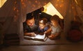 Happy family father and children reading a book in tent at hom Royalty Free Stock Photo