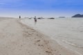 Happy family - father hold baby hand walk in sea on summer vacations with children