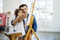 Happy family of father and kid drawing picture, using different paints and brushes. Handsome father and pretty little daughter Royalty Free Stock Photo