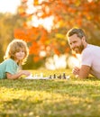 happy family of father man and son child playing chess on green grass in park outdoor, mastermind