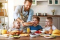 Happy family father with children feeds his sons and daughter in kitchen with Breakfast Royalty Free Stock Photo