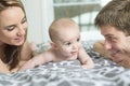 Happy family of father, mother and baby playing in bed Royalty Free Stock Photo