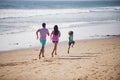 Happy family father, mother and baby son have fun together, child run by water pool along sea surf on black sand beach Royalty Free Stock Photo