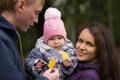 Happy family: Father, Mother and child - in autumn park: dad, mammy baby posing outdoor, girl holding in the hands of