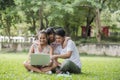 Happy family father, mother and daughter sitting on the grass and playing laptop Royalty Free Stock Photo