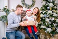 Happy family, father, mother and son, in the morning in living room decorated for Christmas. They open presents and have fun. New Royalty Free Stock Photo