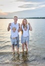 Happy family - father, mother, two sons on the beach with their feet in the water at sunset Royalty Free Stock Photo