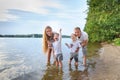 Happy family - father, mother, two sons on the beach with their feet in the water at sunset Royalty Free Stock Photo