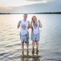 Happy family - father, mother, two sons on the beach with their feet in the water at sunset Royalty Free Stock Photo