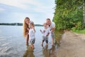 Happy family - father, mother, two sons on the beach with their feet in the water at sunset Royalty Free Stock Photo