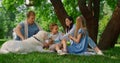 Happy family feeding white dog on picnic. People heve fun on green grass. Royalty Free Stock Photo